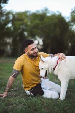 Parkta beyaz köpeği olan genç bir İspanyol.