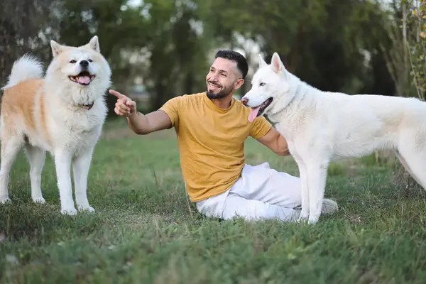 Smiling Man Sitting Ground Pointing Way His Dogs — Stock Photo, Image