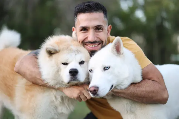 portrait of man hugging his two furry dogs looking at camera