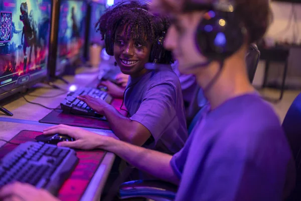 stock image young African American woman looking attentively at her partner's computer while smiling and playing online