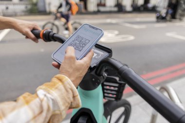 Elektrikli bisiklet şarj istasyonunda akıllı telefonla ödeme yapan adam.