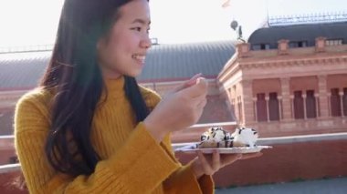 Genç Asyalı kadın güneşli bir günde waffle yiyor.