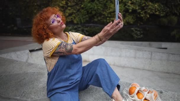 成熟的红头发女人 身上有纹身 带着自拍的照片上传到她的社交网站 — 图库视频影像