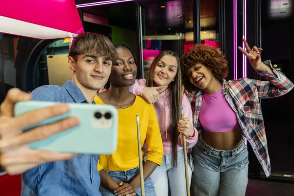 Stock image Selfie of multiracial friends in arcade room playing billiard