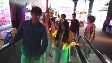 Çok ırklı arkadaşlardan oluşan yürüyen merdivenlere çıkmak, dans etmek ve oyun odasına girerken eğlenmek.