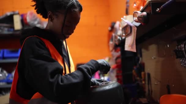 若いアフリカ系アメリカ人女性が修理し 機械工房のカートガレージで車輪をねじる — ストック動画