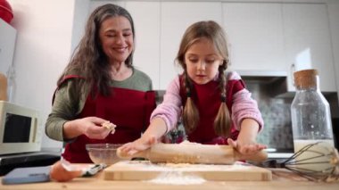 Büyükannesi mutfakta ona yardım ederken torunu hamuru oklavayla yoğuruyor.