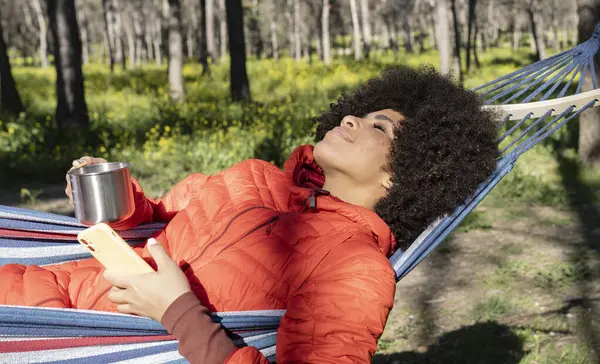Красивая Африканская Американка Лежащая Гамаке Ландшафтной Природе Мобильным Телефоном Руке — стоковое фото