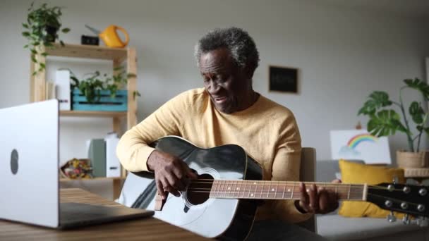 Старший Афроамериканец Учится Играть Гитаре Дома Своими Онлайн Курсами Ноутбуке — стоковое видео
