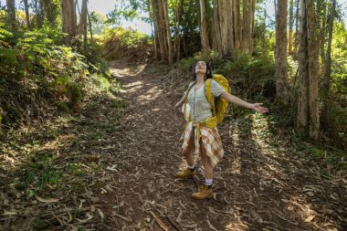 Yürüyüş yolunda kolları açık bir yürüyüşçü kadın.