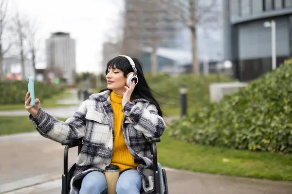 Γυναίκα Αναπηρική Καρέκλα Ακούγοντας Μουσική Ακουστικά Της Ενώ Επιλέγοντας Τραγούδι Εικόνα Αρχείου