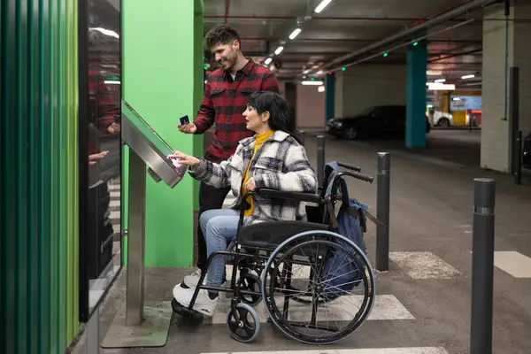 Tekerlekli Sandalyedeki Kadın Yeraltı Otoparkında Para Ödeyen Erkekler Stok Fotoğraf