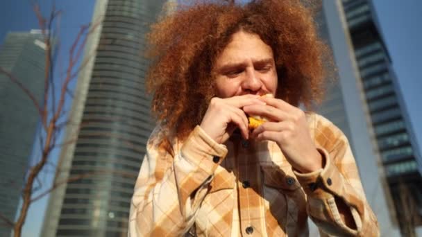 Zoom Ruivo Encaracolado Latino Homem Comendo Hambúrguer — Vídeo de Stock