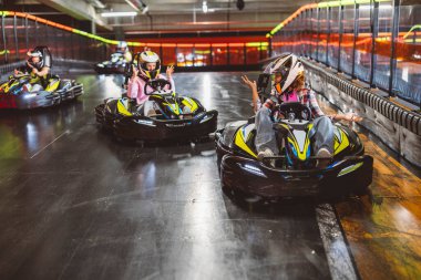 Go kart yarışçısında yarışan arkadaşlar kızgınlıkla ellerini kaldırırken birbirlerinin arabalarına çarptılar. Kapalı kart parçası