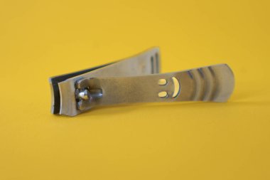 Sarı arka planda paslanmaz çelik tırnak makası var.