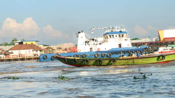 Palembang, Endonezya - 30 Mayıs 2024: Musi Nehri 'nde ağır yüklü bir mavnayı çeken römorkör.