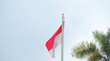 Rüzgarda dalgalanan Endonezya bayrağı ve arka planda kara bulutlar.