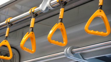 Bu, LRT vagonundaki sarı yolcu kulplarının yakın çekim görüntüsü..