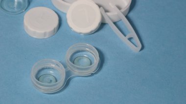 Mavi arka planda cımbız, tutucu ve kontak lensli konteynır