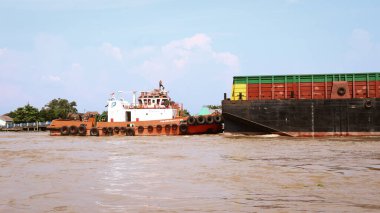 Palembang, Endonezya - 14 Haziran 2024: Palembang 'daki Musi Nehri' ni keşfeden ağır yüklü bir kömür mavnasını çeken römorkör.