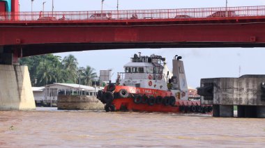 Palembang, Endonezya - 14 Haziran 2024: Musi Nehri 'nde ağır yüklü bir mavnayı çeken römorkör.