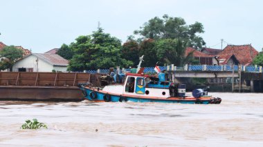 Palembang, Endonezya - 14 Haziran 2024: Palembang 'daki Musi Nehri' ni keşfeden ağır yüklü bir kömür mavnasını çeken römorkör.
