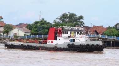  Musi Nehri 'nde ağır yüklü bir mavnayı çeken römorkör..