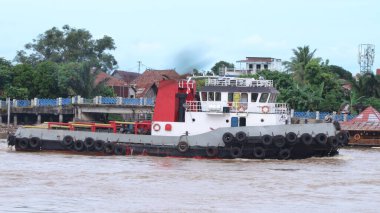  Musi Nehri 'nde ağır yüklü bir mavnayı çeken römorkör..