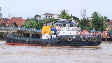  Musi Nehri 'nde ağır yüklü bir mavnayı çeken römorkör..