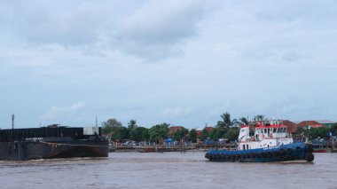  Musi Nehri 'nde ağır yüklü bir mavnayı çeken römorkör..