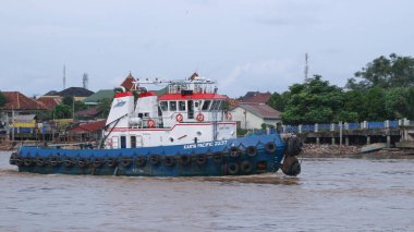  Musi Nehri 'nde ağır yüklü bir mavnayı çeken römorkör..