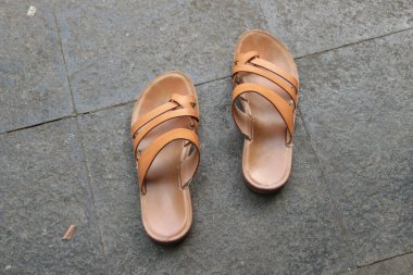 Çimento zemininde izole kahverengi sandaletler..