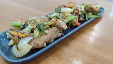 Mavi seramik tabakta tuzlanmış yumurtalı kızarmış tavuk ve beyaz izole edilmiş. Seçici odak.