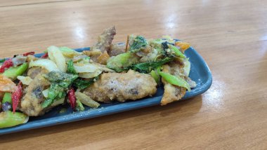 Mavi seramik tabakta tuzlanmış yumurtalı kızarmış tavuk ve beyaz izole edilmiş. Seçici odak.