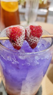 Kelebek bezelyesi, çilek, probiyotik ve üzerinde çilek olan güzel, ferahlatıcı, mor bir buzlu içecek..