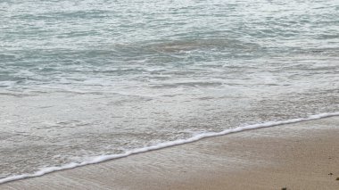 Okyanus sakin ve dalgalar küçük. Su mavinin güzel bir tonu. Gökyüzü açık ve güneş parlıyor.