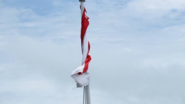 Rüzgarda dalgalanan Endonezya bayrağı ve arka planda kara bulutlar.