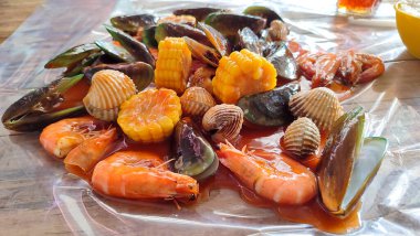 Baharatlı soslu çeşitli deniz ürünlerinin görüntülerini kapat. Midye, karides, yeşil midye, mısır, mürekkep balığı ve yengeç.