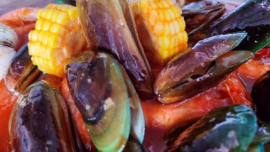 Baharatlı soslu çeşitli deniz ürünlerinin görüntülerini kapat. Midye, karides, yeşil midye, mısır, mürekkep balığı ve yengeç.