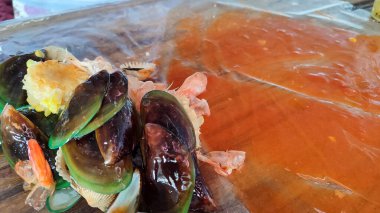 Baharatlı soslu çeşitli deniz ürünlerinin görüntülerini kapat. Midye, karides, yeşil midye, mısır, mürekkep balığı ve yengeç.