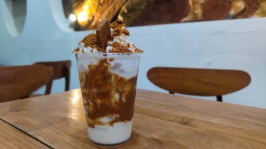 Lotus Biscoff meyveli milkshake, çikolata, krem şanti ve bardakta servis edilen saman sağlıklı içeceğin arka planında izole edilmiş.