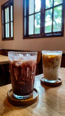 Buzlu çikolatayı yakın çekimde, modern kafede, ahşap masada servis edilir. Buzlu iç döşeme ahşap mobilyalar ve yumuşak ışıklandırma içeriyor..