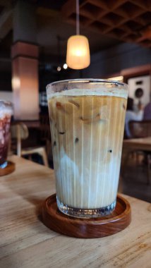 Buzlu çikolatayı yakın çekimde, modern kafede, ahşap masada servis edilir. Buzlu iç döşeme ahşap mobilyalar ve yumuşak ışıklandırma içeriyor..