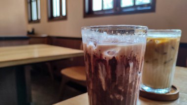 Buzlu çikolatayı yakın çekimde, modern kafede, ahşap masada servis edilir. Buzlu iç döşeme ahşap mobilyalar ve yumuşak ışıklandırma içeriyor..