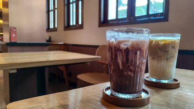 Buzlu çikolatayı yakın çekimde, modern kafede, ahşap masada servis edilir. Buzlu iç döşeme ahşap mobilyalar ve yumuşak ışıklandırma içeriyor..