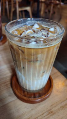 Buzlu çikolatayı yakın çekimde, modern kafede, ahşap masada servis edilir. Buzlu iç döşeme ahşap mobilyalar ve yumuşak ışıklandırma içeriyor..