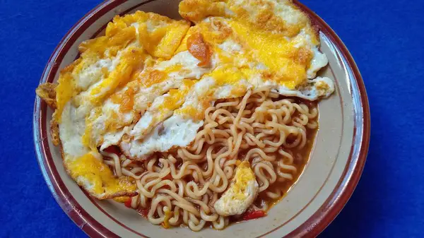 İçinde erişte, yumurta ve sebzeler bulunan bir kase ramen, yemek sunumları ve aşçılık web sitesi kullanımı için mükemmel..