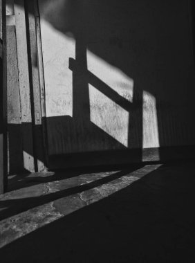 Güneş ışığı, kapıdaki tahta sandalyenin gölgesine neden oluyor. Siyah ve beyaz