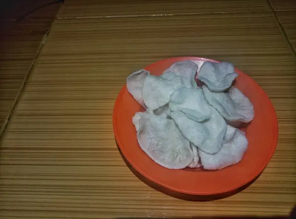 Akşamları fayanslı bir zeminde turuncu bir tabakta kraker ya da kerupuk yığını olan manzara
