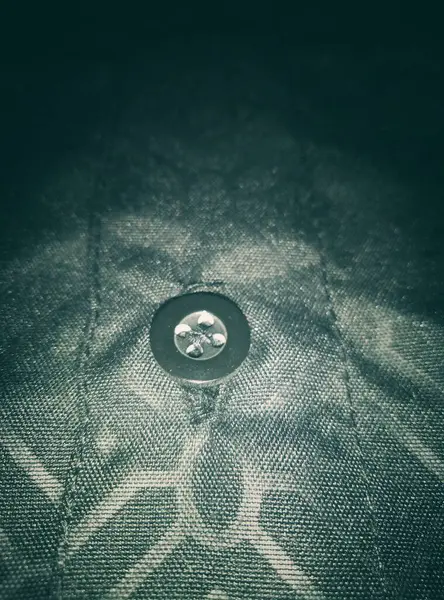 Bu, siyah bir Koko gömleğinin üzerinde gri kabartmalı desenli siyah bir düğme..